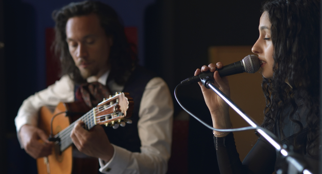 Een vrouw zingt terwijl een man gitaar speelt