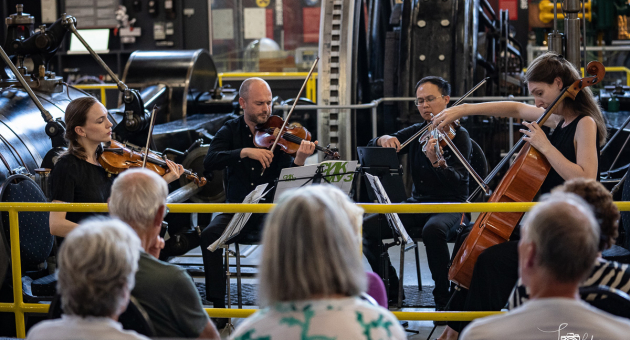 Musici spelen een klassiek concert in een industrieel gebouw.