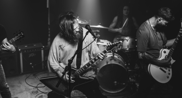 Vier muzikanten spelen samen in een donkere zaal.