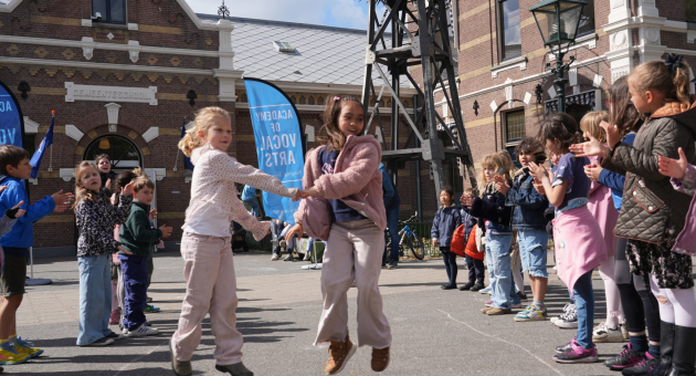 Kinderen springen en klappen in een cirkel, vrolijk en enthousiast.