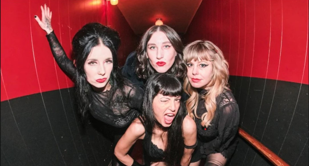 De band The Darts in een zwart-rode hal, passend bij hun energieke all-girl garage-rockimago.