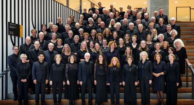 Leden van het Haags Toonkunstkoor gekleed in zwart op de trap in een theater