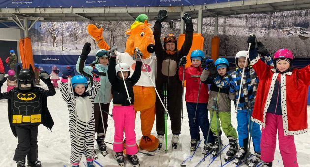 Een groep kinderen in skikleding poseert op een skipiste.