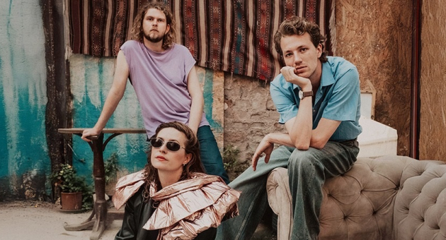 Drie muzikanten poseren met kleurrijke achtergrond