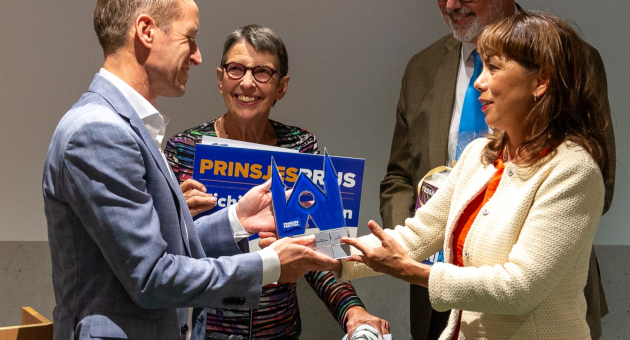 Een groep mensen geeft een prijs tijdens een ceremonie.