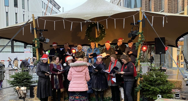 Een kerstkoor verleent een optreden onder een tent in Den Haag.
