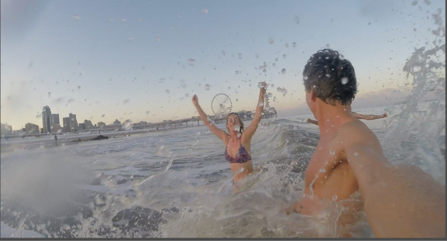 Man en vrouw in het koude water met het reuzenrad en Scheveningen op de achtergrond