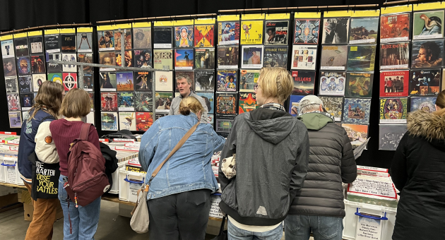 Bezoekers bekijken vintage vinylplaten op een beurs.