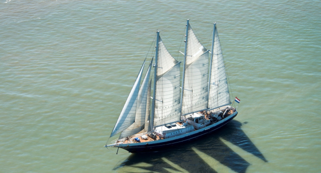 A sailing ship with white sails is sailing on calm water.