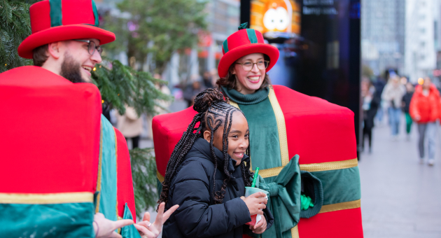 Een meisje poseert met verklede kerstfiguren in Den Haag.