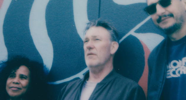 Bandleden van Zuco 103 poseren voor een kleurrijke muur.