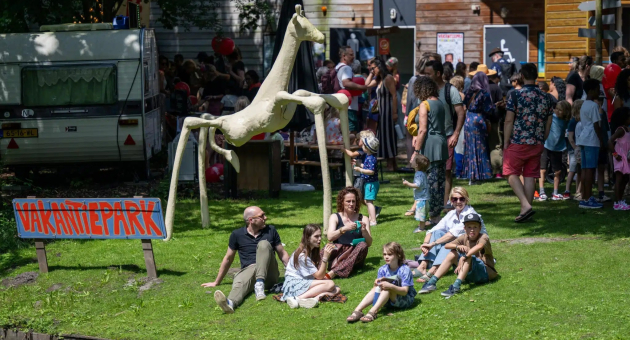 People relaxing at the Vacation Park with a striking sculpture.