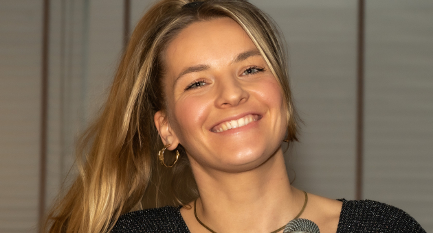 Vrouw met lange blonde haren zingt in een zwart glinsterend top.