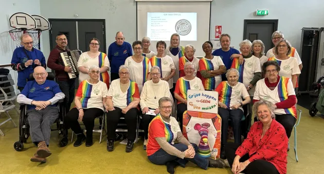 Koor van dames op leeftijd met grijs haar gekleed in witte t-shirts met regenboogkleuren