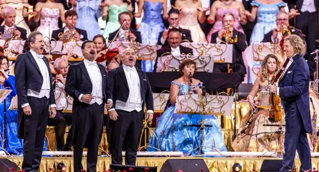 Drie zangers in tuxedo met een orkest op de achtergrond.