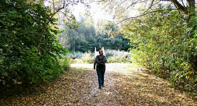 Vrouw wandelt op een pad in een groen park. 