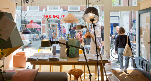 Een blik op een winkelinterieur met lampen en mensen buiten.