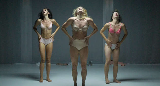 Drie vrouwen in lingerie dansen in een neutrale ruimte.