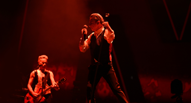 Zanger met microfoon op een podium met bandlid.