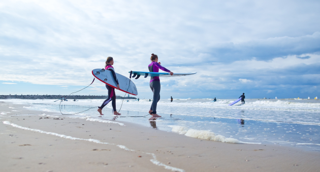 Twee surfers met surfboards onder hun arm in de branding op Scheveningen strand