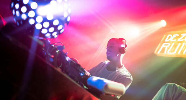 DJ fabel draait muziek in een kleurrijke clubomgeving met verlichting.