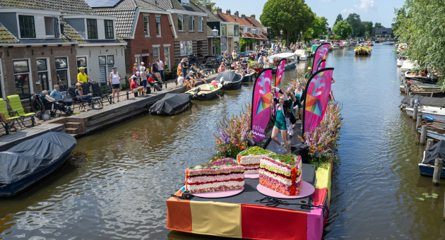 Een bloemenboot met vrolijke decoraties en mensen die eromheen staan.