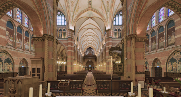 Prachtig onderhouden interieur van de H. Jacobus de Meerdere Kerk. De foto is gemaakt vanaf het altaar en toont de gotische bogen en het pad naar de deur met kerkbankjes aan weerszijden.