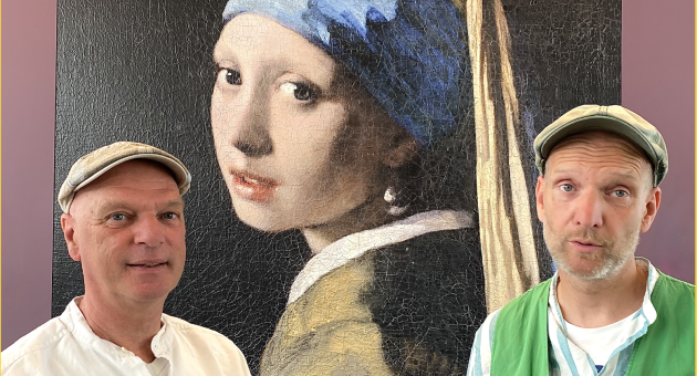 Twee mannen met pet poseren voor een groot kunstwerk van Vermeers Meisje met de parel