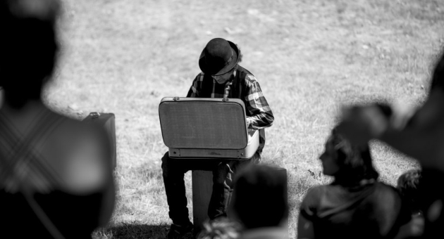Een muzikant in een zwart-wit foto speelt muziek op een koffer.