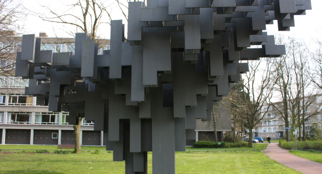 Abstracte sculptuur van zwarte blokken in een park.