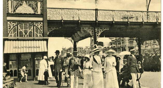 Mensen wandelen op de Boulevard van Scheveningen, omringd door parasols.