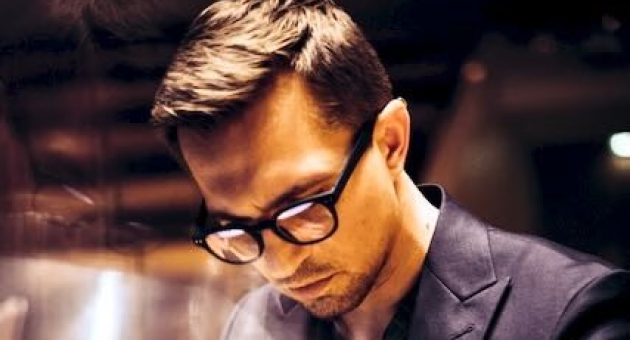 Een jongeman met bril speelt piano