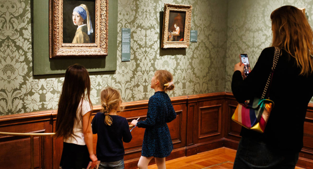 Drie kinderen observeren een schilderij in een museum.