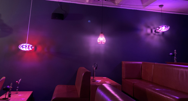 Een interieur met paarse, moderne lampen en leren banken.