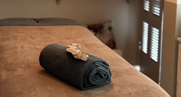 Massagekamer met opgerolde handdoek en edelstenen op een behandeltafel, gedimd licht en rustgevende sfeer