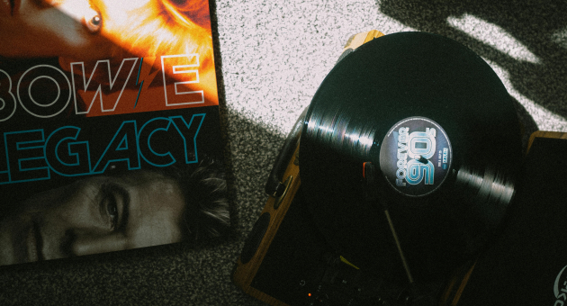 Langspeelplaat met 'Forever 90s' draait op platenspeler naast albumhoes van David Bowie Legacy op grijze vloer