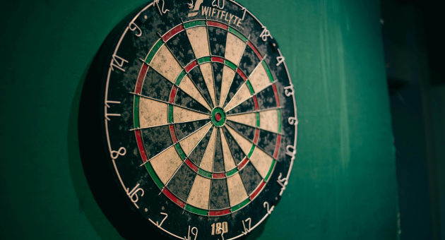 Een dartbord aan een groene muur