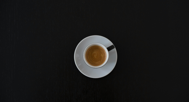 Een espresso in een witte kop op een zwarte tafel