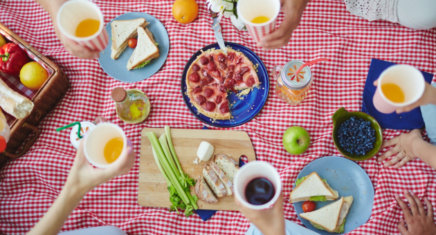 Groep mensen geniet van een picknick met eten en drinken.