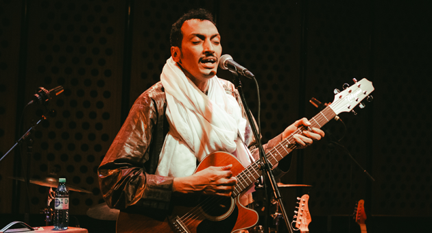 Foto van gitarist Bombino terwijl hij gitaar speelt.