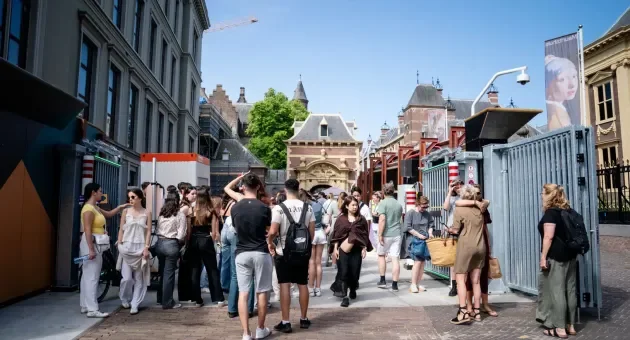 Mensen staan in een drukke straat met historische gebouwen.