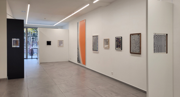 Moderne galerie met strakke witte muren, geometrische kunst aan de wand en daglicht van achterin de ruimte