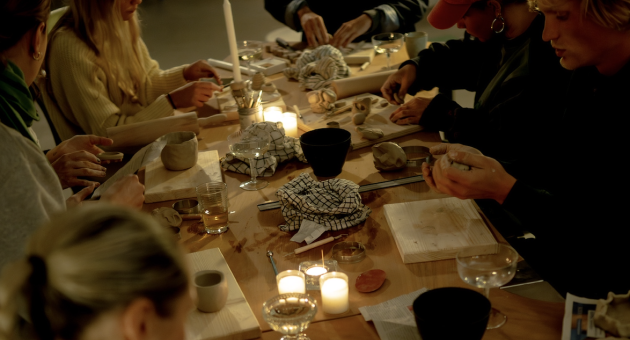 Groep mensen werkt samen aan kleiprojecten aan tafel.
