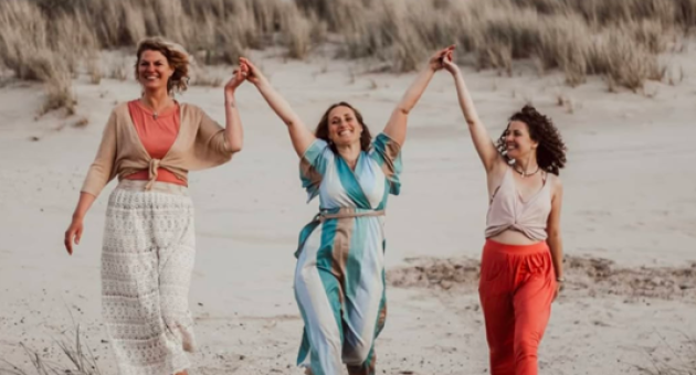 Drie vrouwen hand in hand wandelen op het strand
