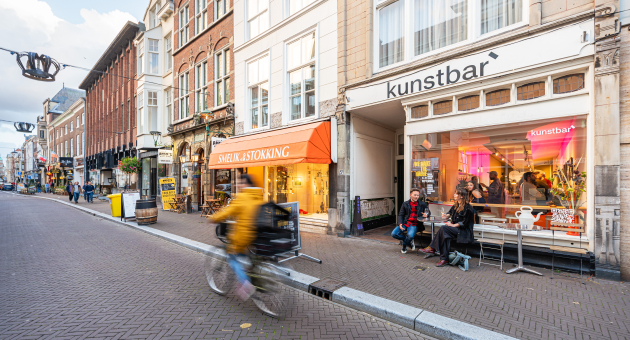 Een drukke straat in Den Haag met winkels en cafés.