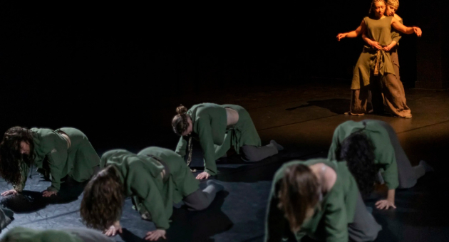 Groep dansers in groene outfits performen op het podium.