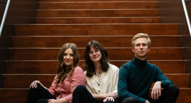 Drie leden van het zeewier-ensemble zitten samen op een trap