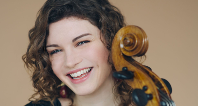 Stralende jonge vrouw met krullend haar en een cello, klaar om te spelen.