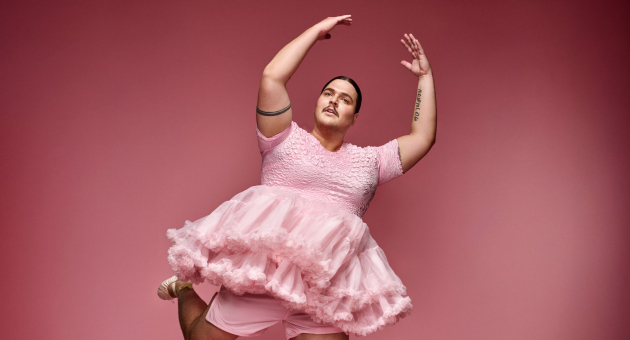 Fimme bakker draagt een roze jurk en staat in een balletpose voor een donkerroze achtergrond. 