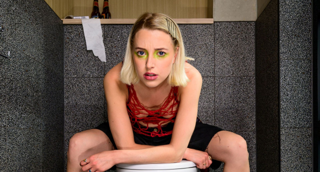 Meisje die op toiletbril zit kijkend in de camera